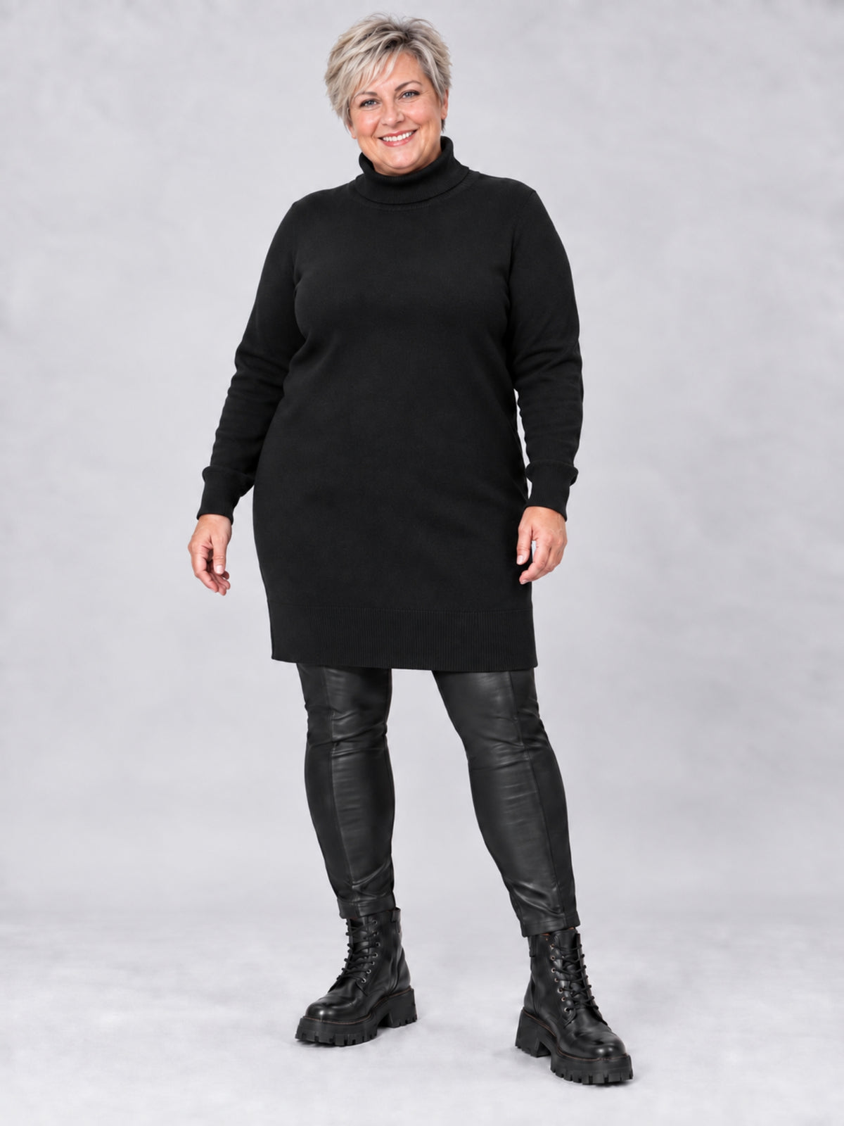 Schwarzer Rollkragenpullover in langer gerader Form, getragen mit schwarzer Lederhose, Vorderansicht