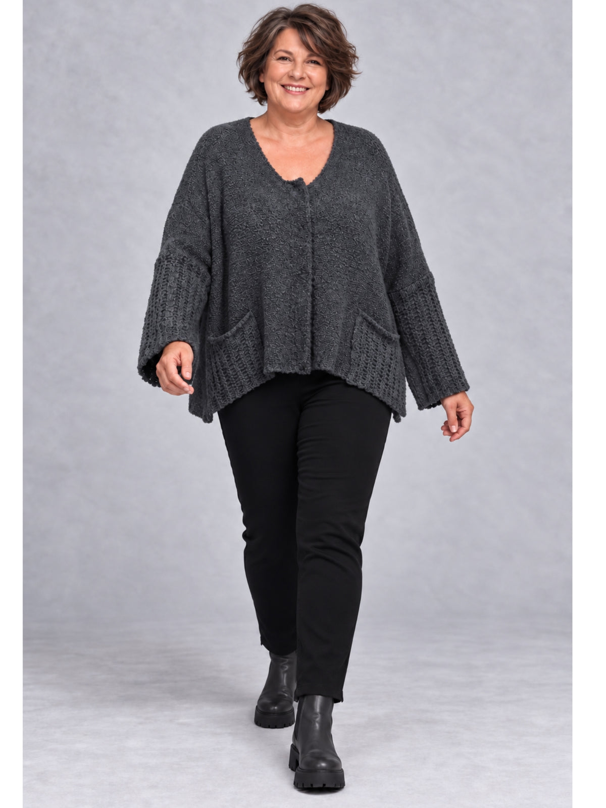 Dunkelgraue Kurzstrickjacke getragen mit schwarzer Hose und Stiefeletten