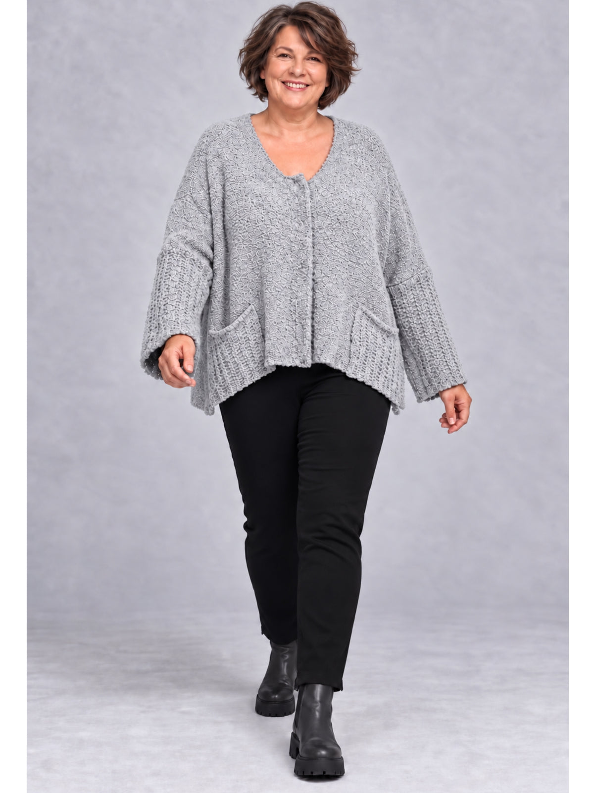 Hellgraue Kurzstrickjacke getragen mit schwarzer Hose und Stiefeletten