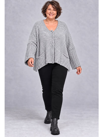 Hellgraue Kurzstrickjacke getragen mit schwarzer Hose und Stiefeletten