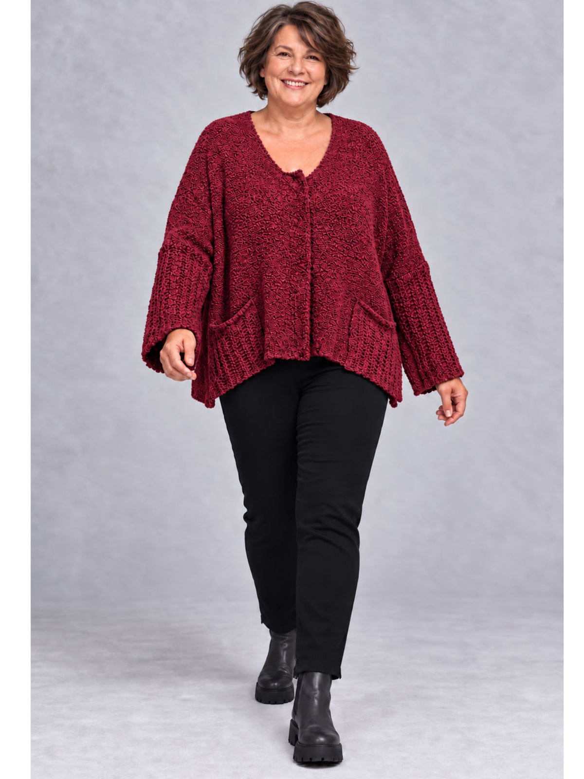 Weinrote Kurzstrickjacke getragen mit schwarzer Hose und Stiefeletten
