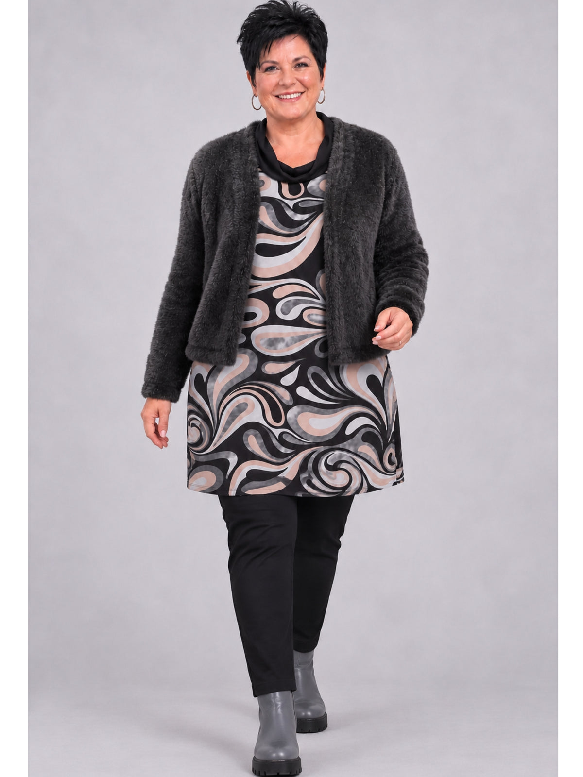 Schwarze Kurzjacke getragen mit Tunika im Wellenmuster, schwarzer Hose und grauen Stiefeletten, ganze Ansicht