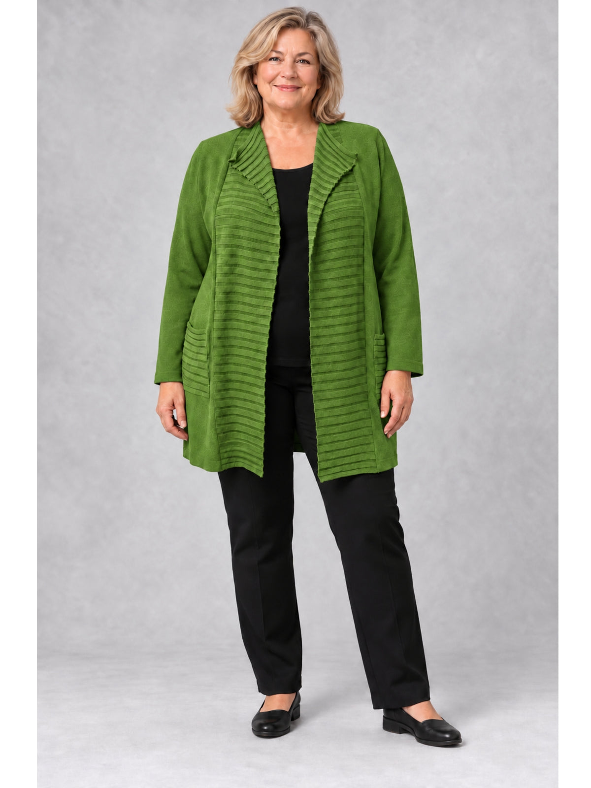 Grüne lange Feinstrickjacke mit Querrippen, getragen mit schwarzem Shirt und schwarzer Hose
