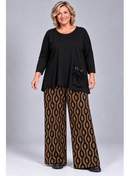 Weite Marlene-Hose von Naveed im Ketten-Muster in Cognac und Schwarz, getragen mit schwarzem Pullover mit Ösen-Tasche