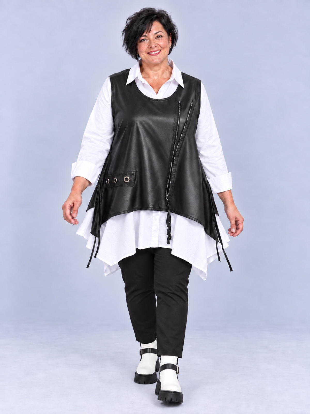 Schwarzes Kunstleder-Überwurf-Top, getragen über weißer Bluse und schwarzer Hose