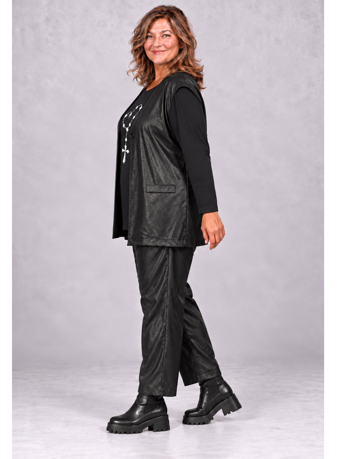 Schwarze Weste mit Taschenpatte über Langarmshirt und passender Hose getragen, seitliche Ansicht