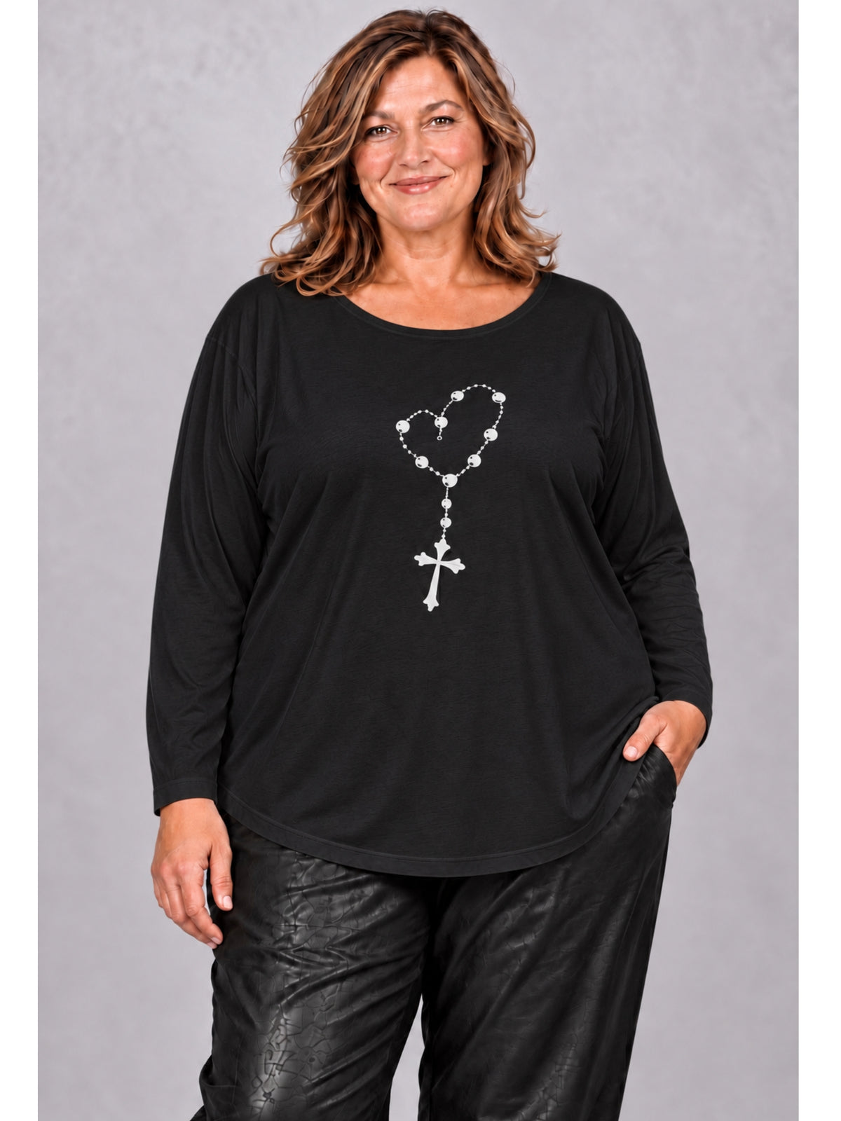 Schwarzes Langarmshirt von Sophia Curvy mit aufgedruckter Kreuzkette im Herz, getragen zur schwarzen Hose, Vorderansicht