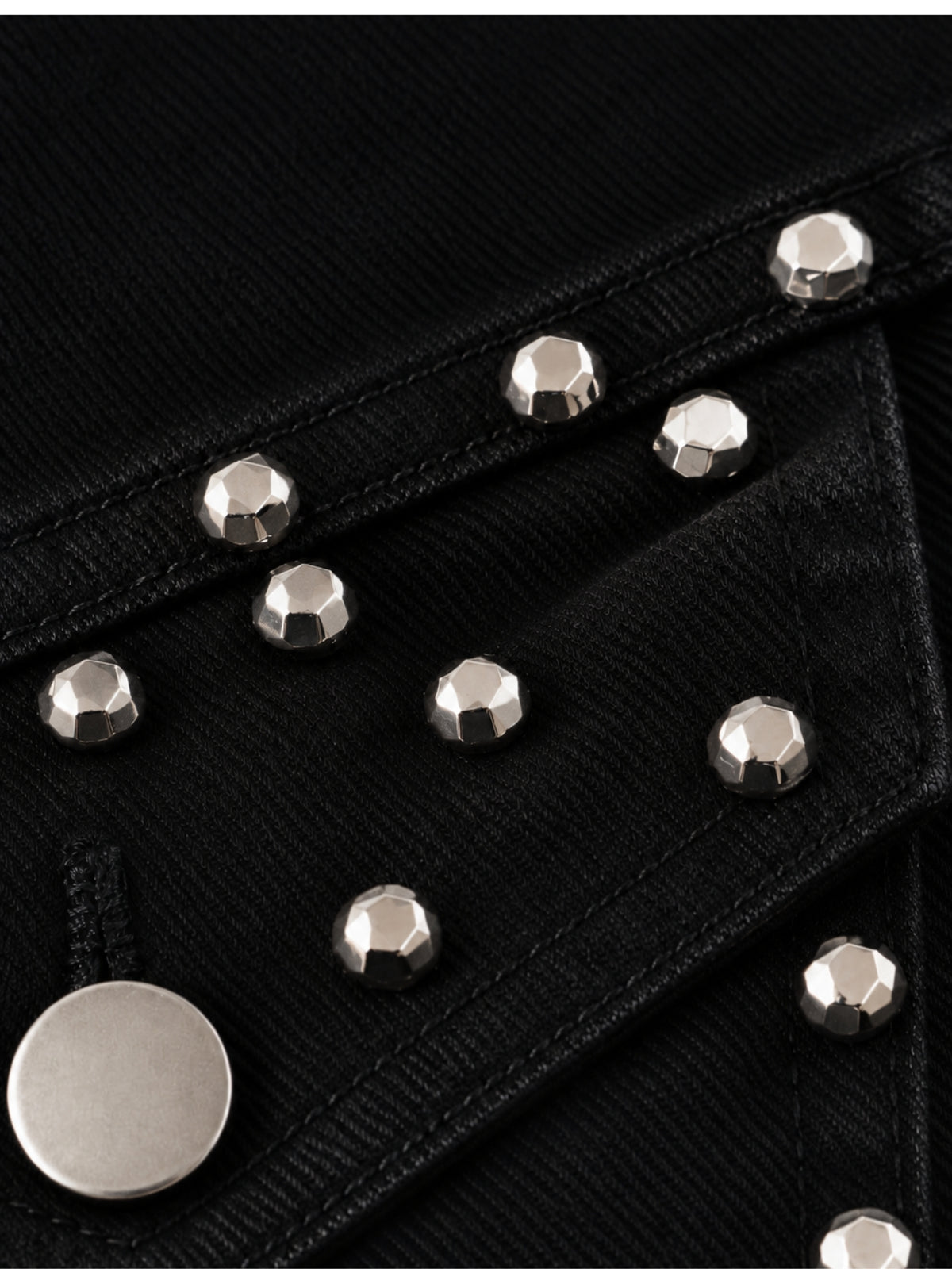 Geschliffene silberne Nieten an der Brusttaschenpatte der schwarzen Jeansjacke, Detailansicht