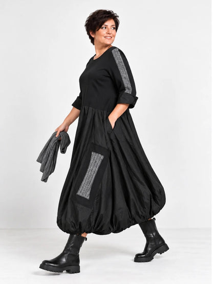 Schwarzes Ballonkleid in großen Größen von der Seite, Hand in der seitlichen Eingrifftasche