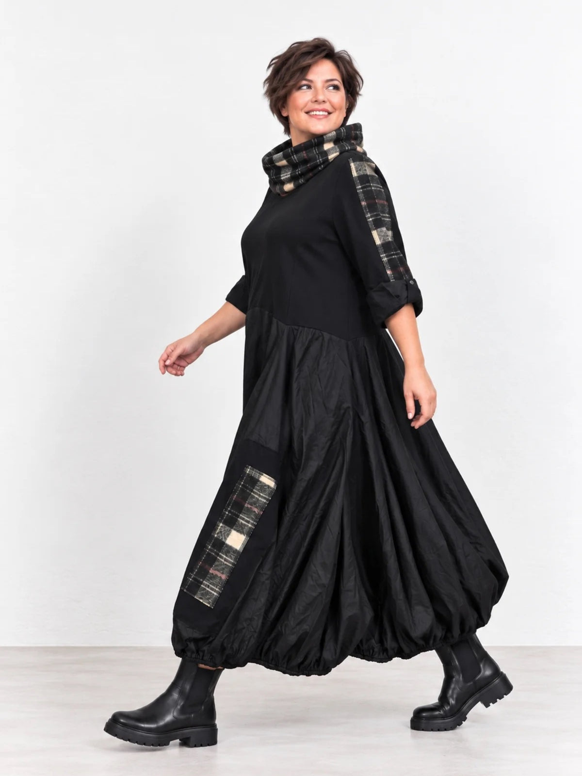 Schwarzes Ballonkleid in großen Größen von der Seite, karierte Tasche und karierter Rollkragen